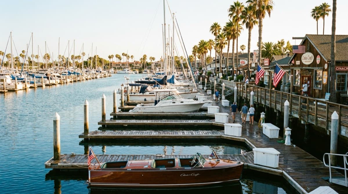 Marina with rows of wet slip boat docks and sailboats in calm water